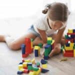 A young girl plays with wooden building blocks