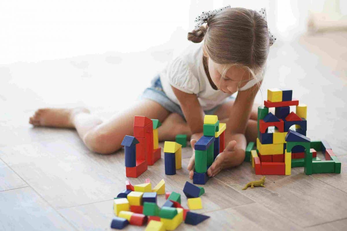 A young girl plays with wooden building blocks