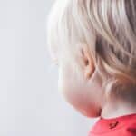 A small blonde-haired child looks away from the camera